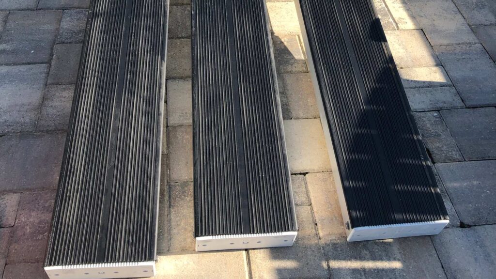 Three replacement boat lift bunks with black rubber covers on a paver surface