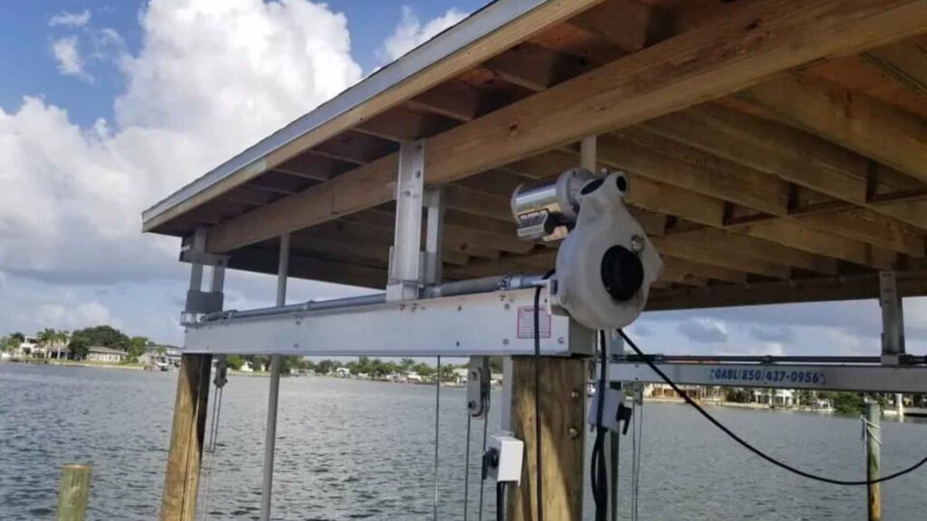 Covered boat lift system with aluminum beams and electric motor installed on dock pilings