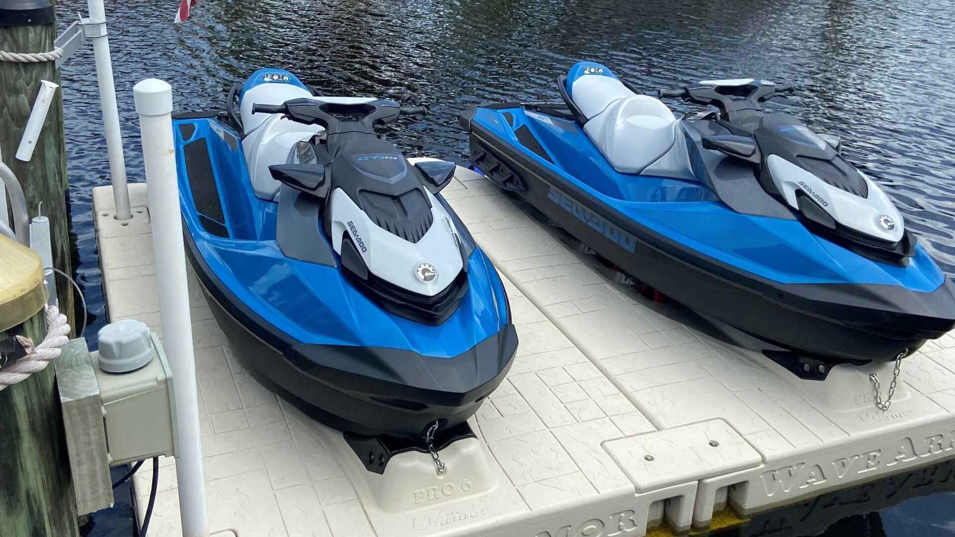 Two blue Sea-Doo jet skis docked on Wave Armor Jet Ski Docks in a residential canal