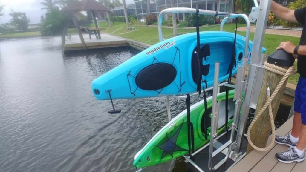 Dual kayak lift holding blue SunDolphin and green Emotion kayaks upright on a canal dock