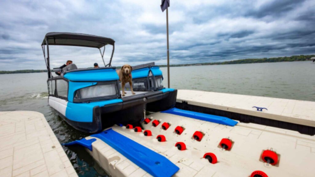 Electric pontoon boat with a dog docking on a Wave Armor boat port with red rollers