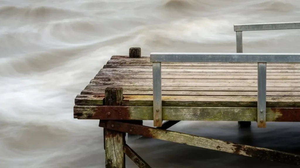 Old wooden dock with visible rot and corrosion, surrounded by water.