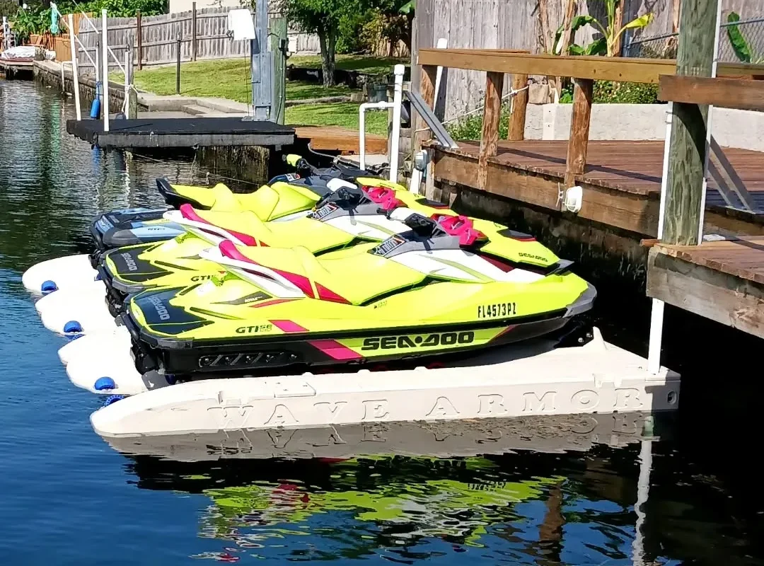Best Jet Ski Docks comparison: A row of lime green and black Sea-Doo GTI personal watercraft parked on a tan Wave Armor modular floating dock system.