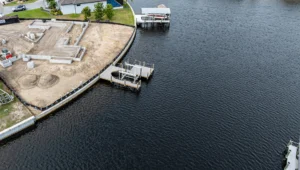 Aerial view of an aluminum boat lift and dock installed along a curved seawall on a Florida canal.