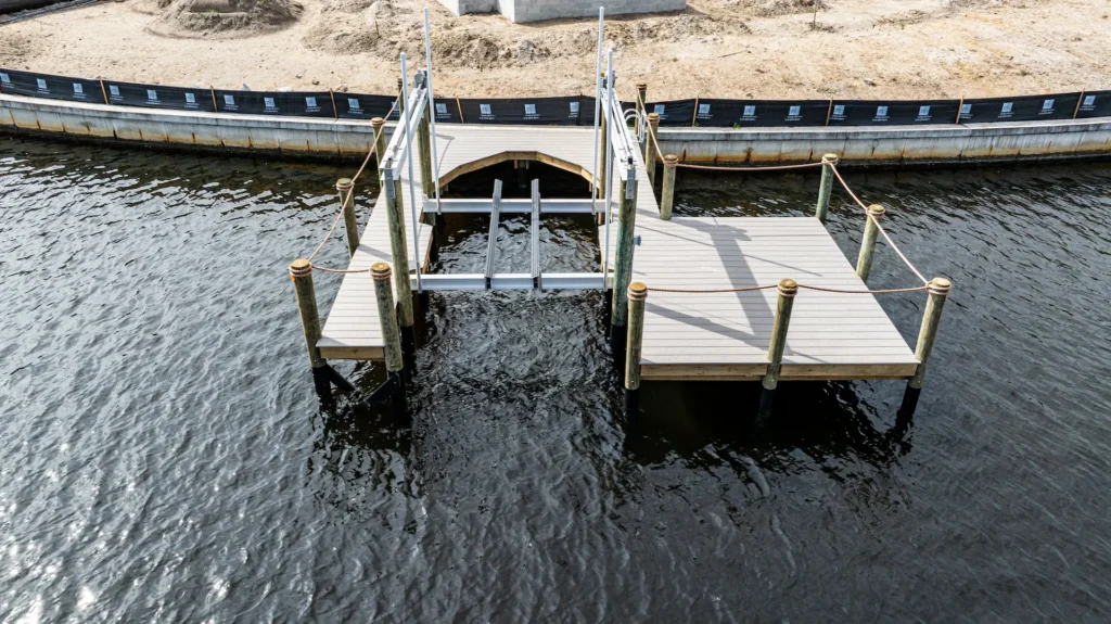 Aerial close-up of an aluminum boat lift and newly built dock installed along a Florida seawall.