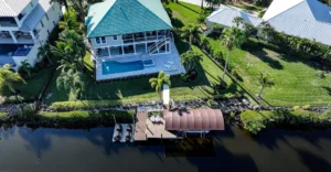 Angled aerial view of a residential Florida waterfront with a boat lift canopy and dock system.