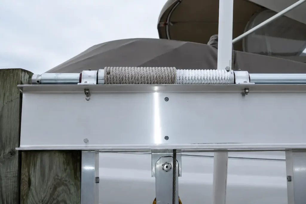 Close-up of a boat lift cable replacement system showing a worn cable and winch drum on an aluminum boat lift, highlighting components inspected during professional boat lift cable replacement and maintenance.