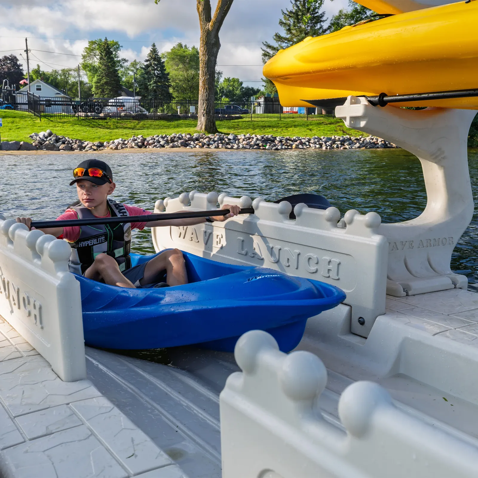 Boy launching his kayak from a Wave Armor Kayak Launch with 2 Rails into calm water
